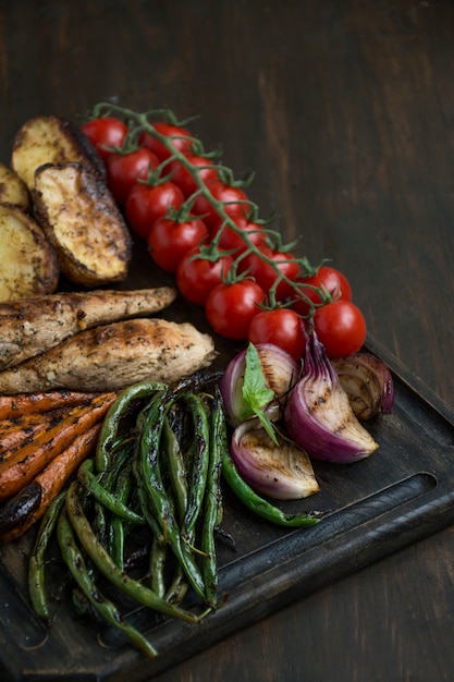 Verduras a la parrilla sobre una tabla para cortar en madera oscura.