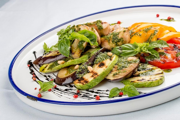 Verduras a la parrilla tomates calabacín berenjena pimiento dulce champiñones en un plato blanco