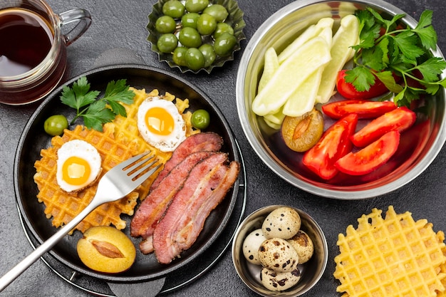 Verduras picadas y hierbas en un bol Bacon gofres huevos fritos y un tenedor en una sartén