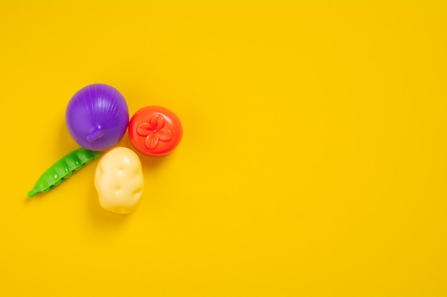 Verduras de plástico sobre un fondo amarillo con espacio de copia Comida plana de plástico alimentación saludable