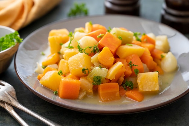 Verduras de raíz asadas o al horno con hierbas frescas verduras de naranja en un plato Comida vegana