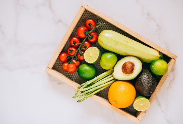 Verduras saludables frescas en caja de madera sobre fondo de mármol blanco