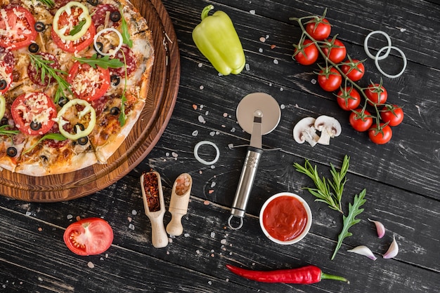 Foto verduras, setas y pizza de los tomates en un fondo de madera negro. se puede utilizar como fondo.