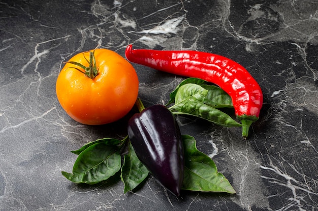 Verduras sobre un fondo gris Tomate pimiento rojo y negro