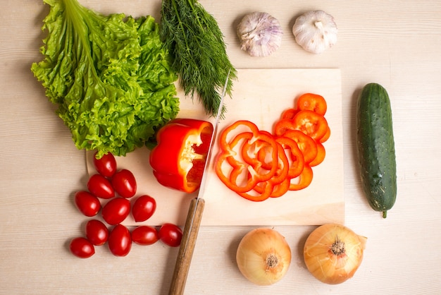 Verduras, tabla de cortar y cuchillo sobre una mesa