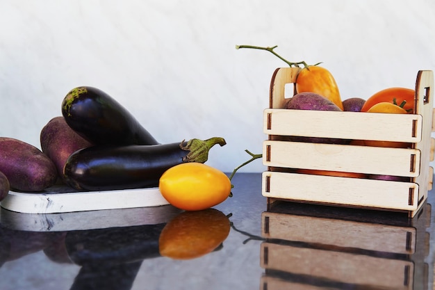 Verduras de temporada en caja de madera y en podios tomates frescos papas moradas berenjenas zanahorias pepinos pimiento dulce Preocupación ecológica compras ecológicas Comida justa