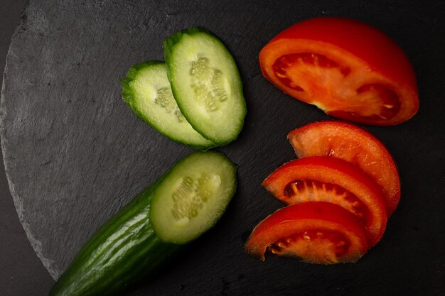 Verduras tomate y pepino sobre fondo negro