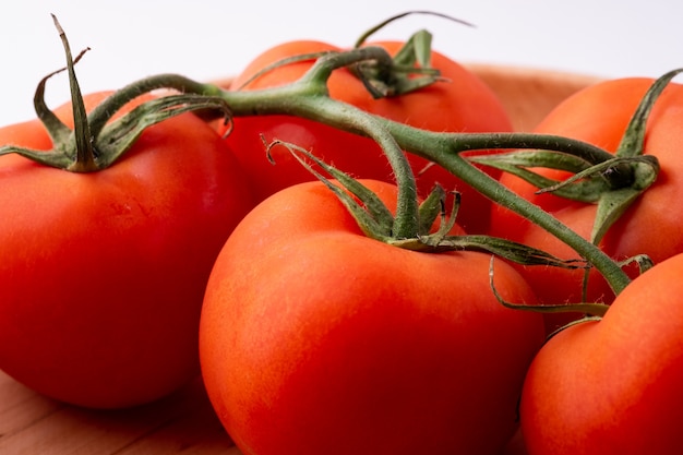 Verduras de tomate en placa de madera aislada en blanco de cerca