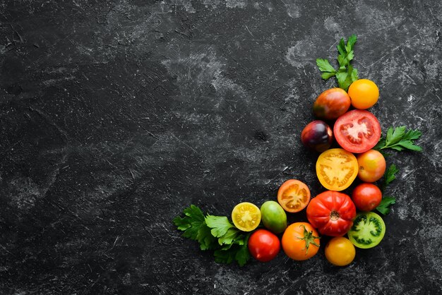 Verduras Tomates frescos de colores Sobre un fondo de piedra negra Vista superior Espacio libre para el texto