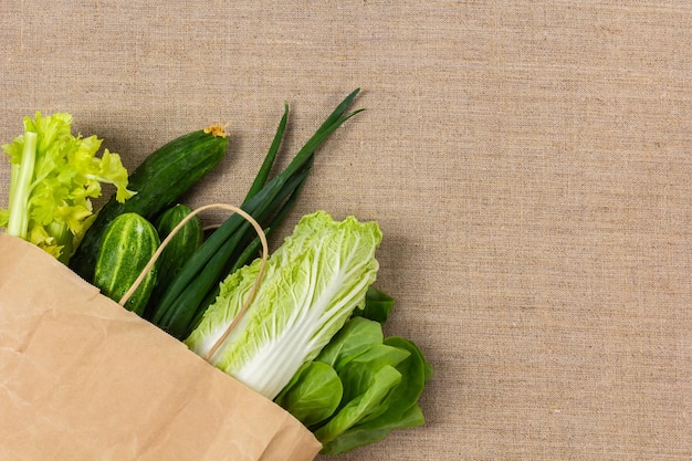 Verduras verdes frescas en bolsa de papel sobre fondo de arpillera y espacio de copia