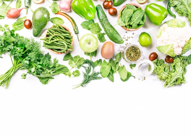 Verduras verdes, hierbas, frijoles y frutas, comer sano y limpio, verduras de hoja, semillas, superalimentos sobre fondo blanco, fuente de proteína vegetariana y nutrición dietética de desintoxicación.