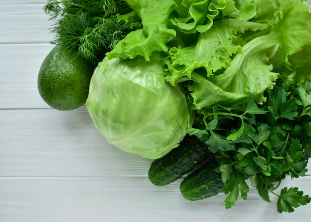 Verduras verdes sobre fondo blanco de madera Ensalada col pepino eneldo perejil aguacate