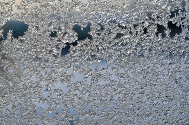 Vereisung auf Fensterglas, Frost auf Hintergrund des blauen Himmels im Winter