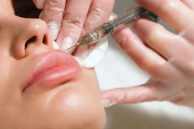 Verfahren zur Korrektur der Lippenform in einem Kosmetiksalon. Der Spezialist spritzt auf die Lippen