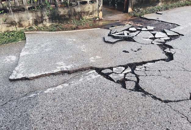 Verfallene Straße, asphaltierte Straßenoberfläche mit beschädigter, abblätternder beschädigter Straße, die auf die Straßenreparaturfahrbahn wartet
