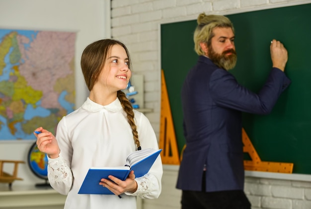 Verfolgen Sie den Fortschritt der Schüler Kleines Mädchen liest Buch Prüfung oder Lektion Zurück zur Schule Wer ist heute im Dienst Entwicklung der Kindheitserziehung Schüler und Lehrer im Klassenzimmer Schulmädchen schreibt Notizen