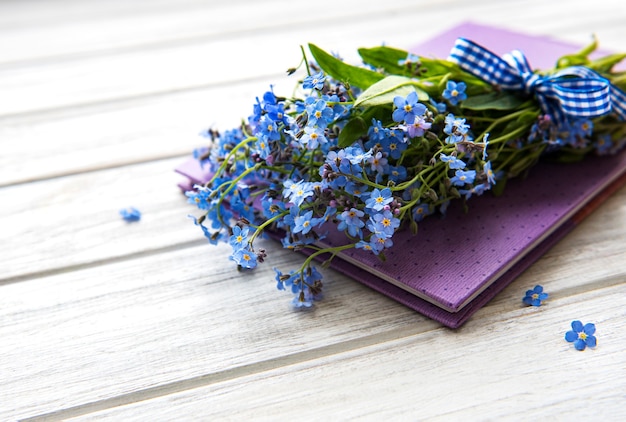 Vergiss mir nicht Blumen und Notizbuch auf weißem Holz