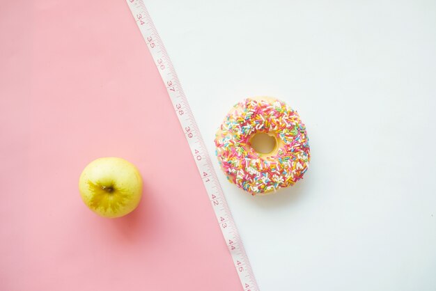 Vergleich von Donuts mit grünem Apfel auf Farbfläche