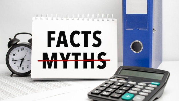 Vergleich von Fakten und Mythen auf Notizblock mit Wecker und Taschenrechner