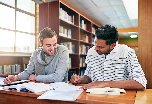 Vergleichen wir unsere Notizen Aufnahme von zwei Universitätsstudenten, die in der Bibliothek auf dem Campus zusammenarbeiten