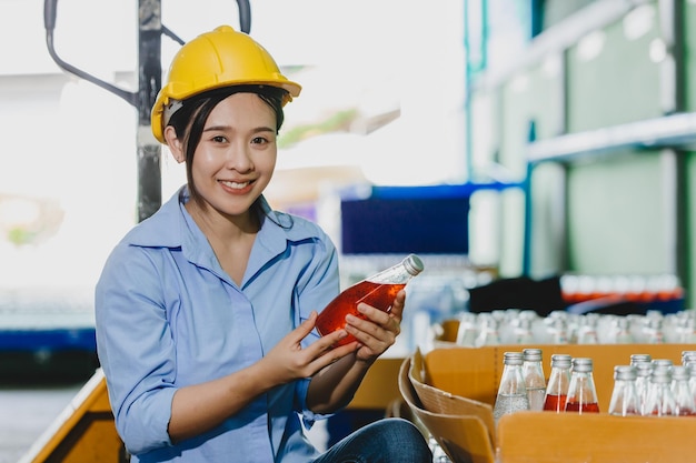 Verificação de qualidade de produtos femininos asiáticos retrato trabalhador sorriso com teste de produto de bebida antes do envio