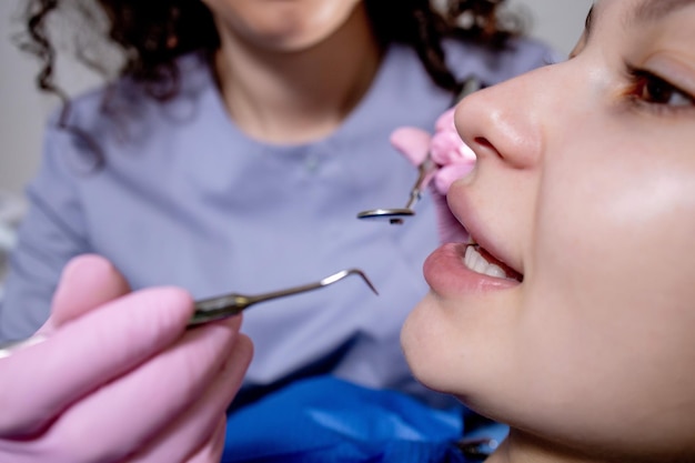 Verificação de saúde o dentista no centro de estomatologia está examinando os dentes da mulher usando ferramentas odontológicas