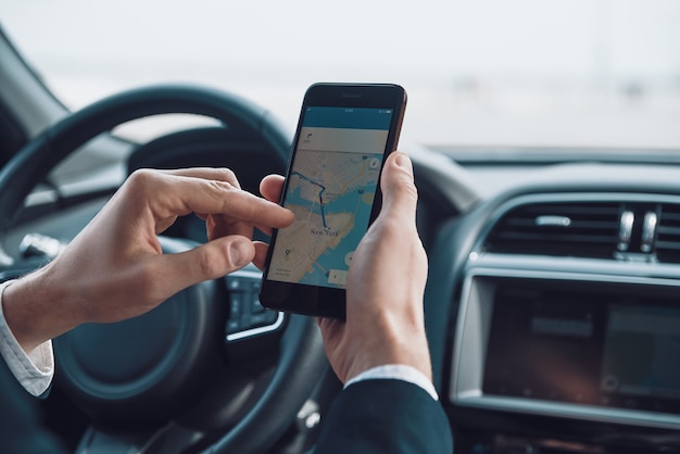 Foto verificando a direção. close-up de jovem usando telefone inteligente para verificar o mapa enquanto dirige um carro