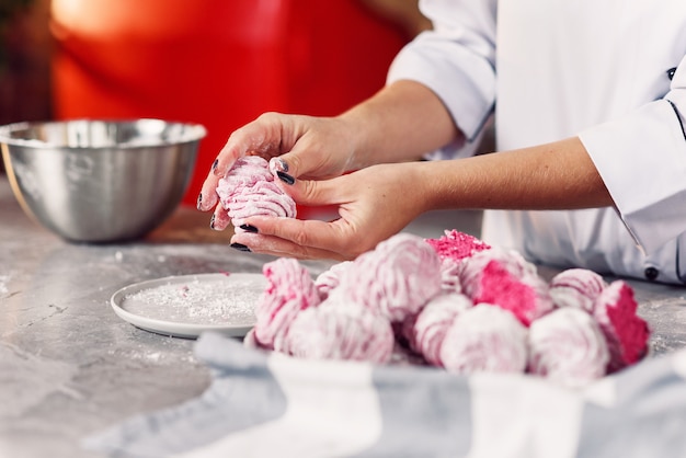 Verificando a qualidade do marshmallow caseiro. Feche as mãos do chef com marshmallows feitos frescos.