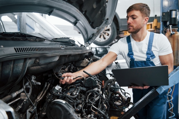 Verificando detalhes. Empregada com uniforme azul trabalha no salão automóvel.