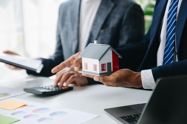 Foto verkäufer hands-on-haus-modell kleines spielzeughaus kleine hypothek immobilienversicherung und konzepte immobilien im büro