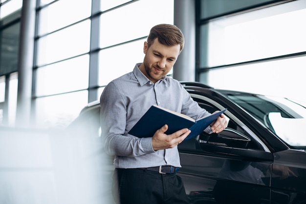 Verkäufer im Autohaus, der am Auto steht