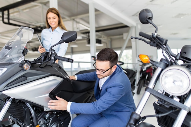 Verkäuferin im Ausstellungsraum des Autohauses im Gespräch mit dem Kunden und hilft ihm bei der Auswahl eines neuen Motorrads für sich.
