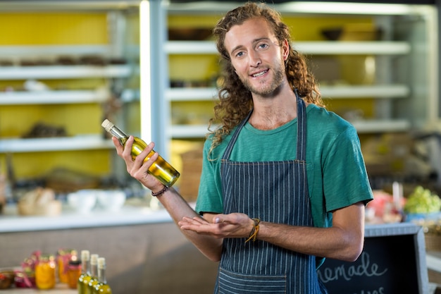 Verkäuferin zeigt eine Flasche Olivenöl