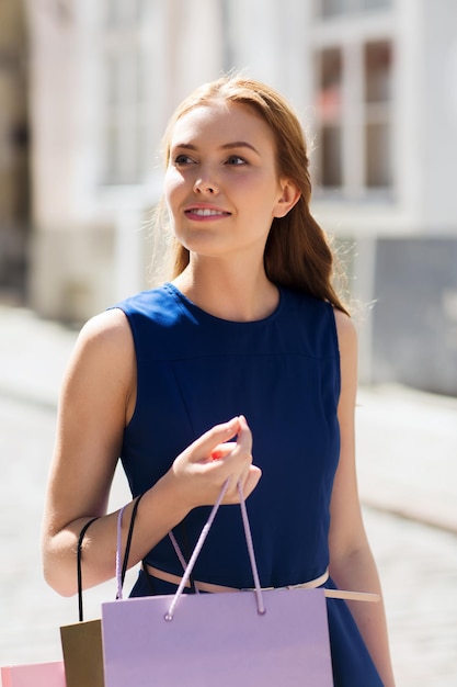 Verkauf, Konsum und Menschen Konzept - glückliche junge Frau mit Einkaufstüten zu Fuß entlang Stadt Straße