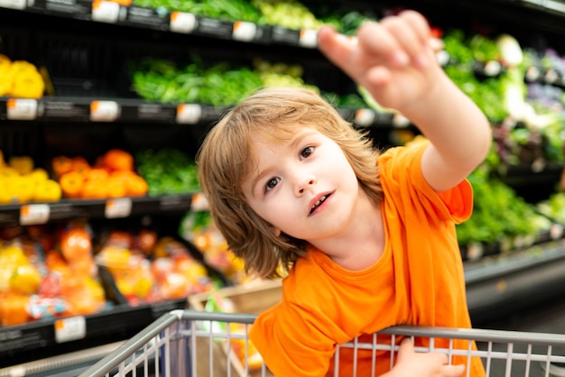 Verkauf Konsum und Menschen Konzept Kinder mit Lebensmitteln im Einkaufswagen im Lebensmittelgeschäft