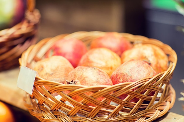 Verkaufs-, Einkaufs- und Öko-Lebensmittelkonzept - reife Granatäpfel im Korb mit Namensschild auf dem Lebensmittelmarkt