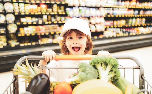 Verkaufskonsum und Menschenkonzept begeisterte Kinder mit Lebensmitteln im Einkaufswagen im Lebensmittelgeschäft