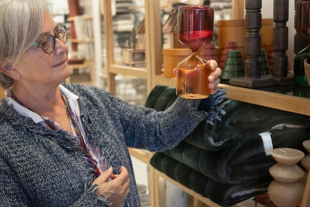 Foto verkaufszeit die ältere frau mit brille betrachtet die im haushaltswarengeschäft ausgestellten artikel