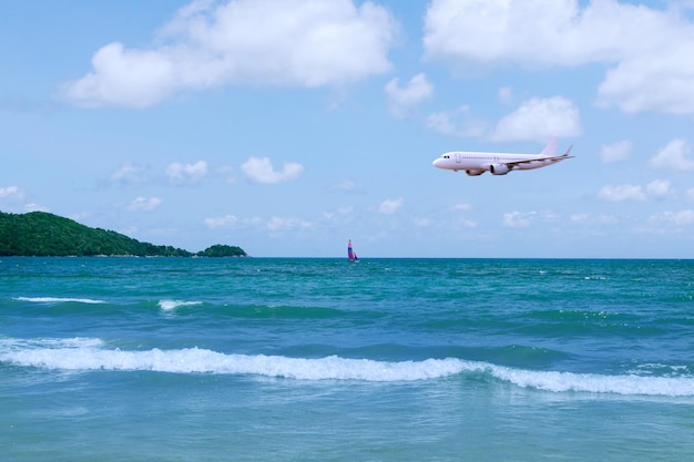 Verkehrsflugzeug über dem Meer in der Sommersaison und klarer blauer Himmel über wunderschöner Landschaft, Sandstrand im Hintergrund. Konzept für Geschäftsreisen und Transport im Sommerurlaub