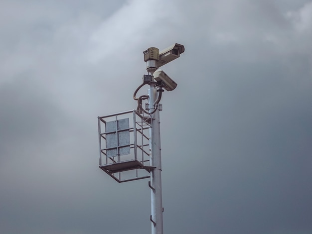 Verkehrsüberwachungskamera auf einem hohen Turmmmast und dramatischer grauer Himmelhintergrund