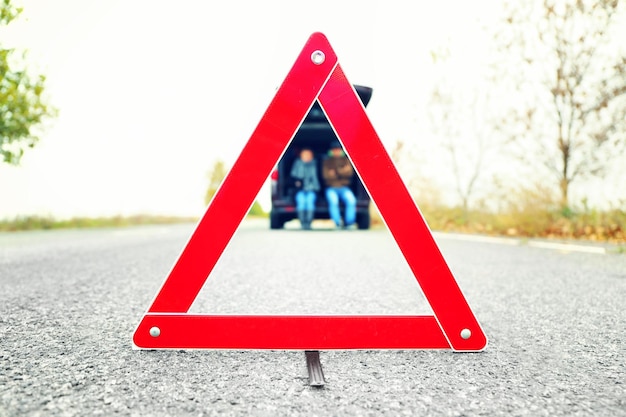 Verkehrswarnschild auf der Straße mit Auto und Paar im Hintergrund