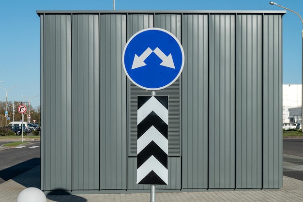 Verkehrszeichen-Umleitungshindernis Ein blaues Schild mit zwei Pfeilen und vertikalen Markierungen in der Nähe