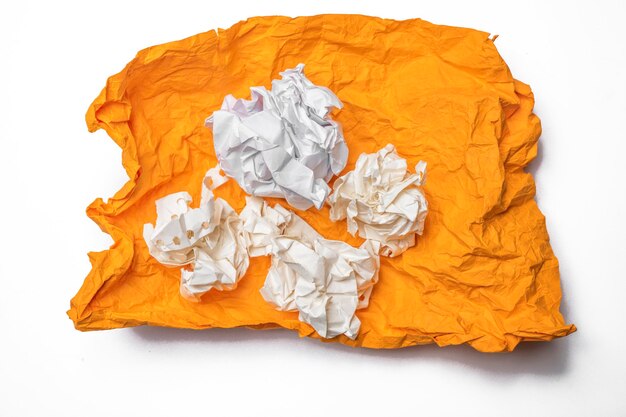 Verkrümmte Papierkugeln auf einem offenen, auf weißem Hintergrund isolierten orangefarbenen Papier