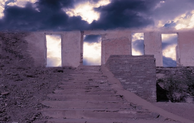 Verlassene alte große Steinmauer mit einer Treppe auf einem Felsen unter einem dramatischen bewölkten Himmel