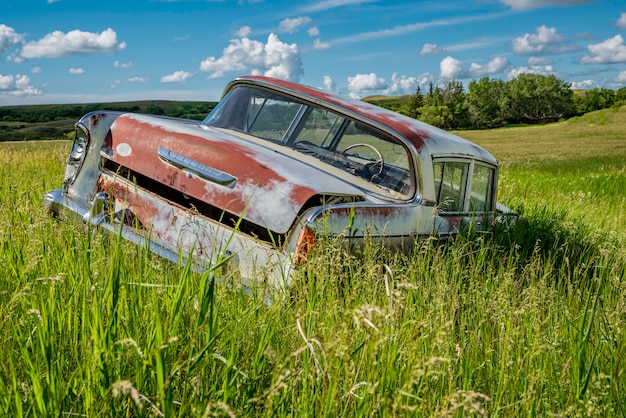 Verlassene antike blaue Limousine im hohen Gras auf einem Hügel