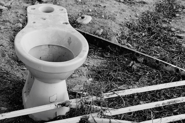 Foto verlassene toilettenschüssel auf dem feld mit rostigem metallischen geländer