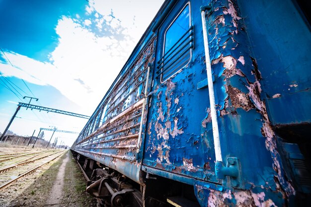 Verlassener Bahnhof. Rostige verwitterte abgezogene Farbe eines alten Lastwagens. Blauer Eisenbahnwagen. Holzschwellen oder Querschwellen