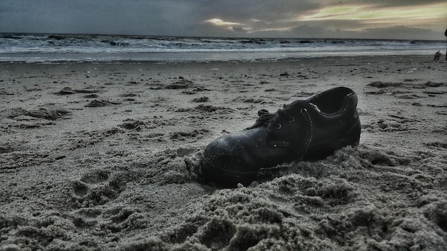 Foto verlassener schuh am sandstrand bei sonnenuntergang