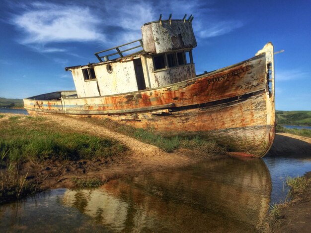 Foto verlassenes boot am flussufer vor blauem himmel