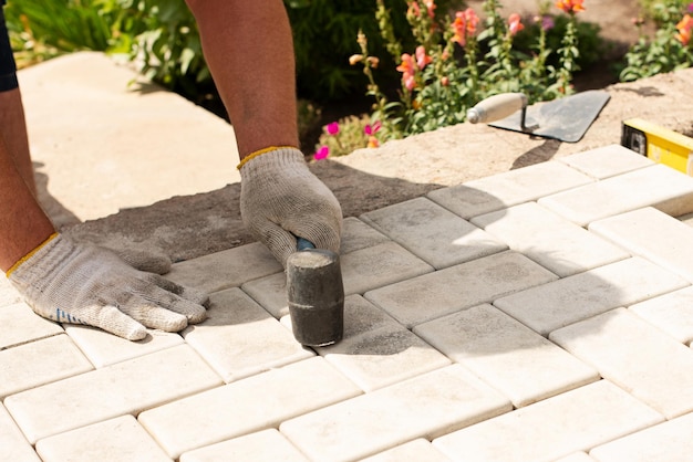 Verlegung von grauen Betonpflasterplatten im Innenhof des Hauses auf einer Sandgrundlage